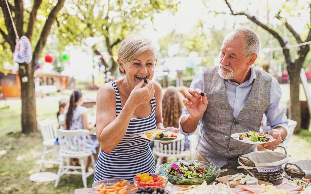 older couple eating food at an outdoor picnic