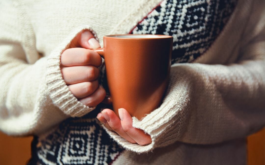 woman in sweater holding cup of coffee